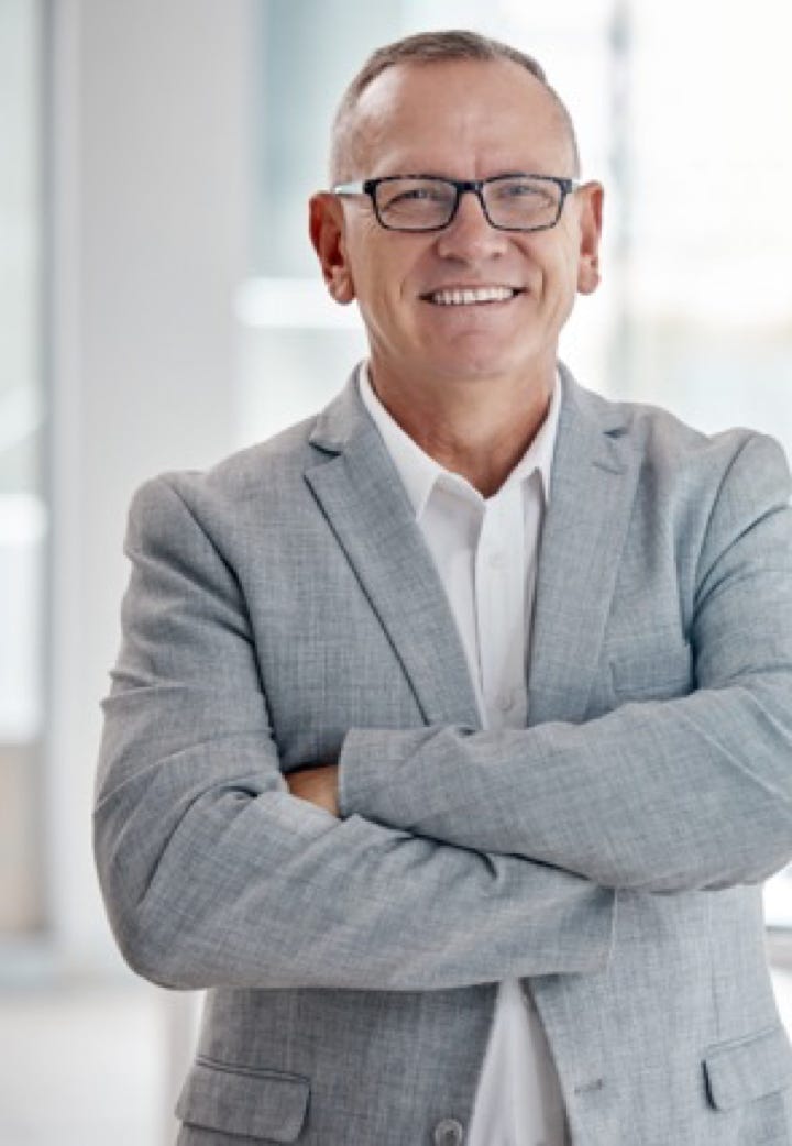 Casual smart dressed man smiling  and stood with his arms folded